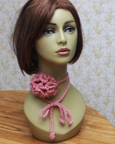 a mannequin head with a pink crochet scarf around it's neck