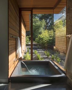 an outdoor jacuzzi tub in the middle of a room with wood walls and windows