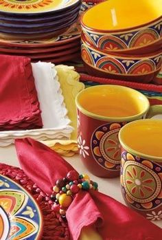 a table topped with plates and cups filled with colorfully decorated dishes next to each other