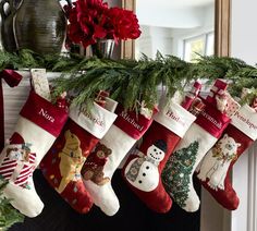 christmas stockings hanging from a mantel decorated with poinsettis and snowmen