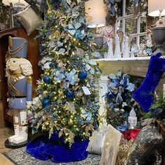 a christmas tree with blue and silver decorations in a room filled with other holiday items