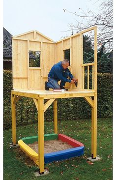 a man is building a small house out of wood and sandboxes in the yard