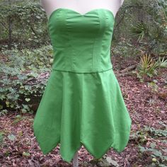 a green dress sitting on top of a mannequin's head in the woods