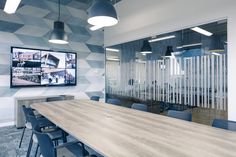 an office meeting room with a large wooden table and blue chairs in front of a flat screen tv