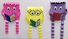 three paper monsters are hanging on the wall and one is reading a book while the other has glasses