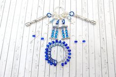 blue glass beads and necklaces are arranged on a white wooden surface with wood planks