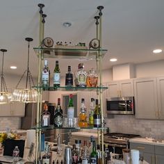 a kitchen filled with lots of bottles and glasses on top of a metal shelf next to a counter