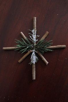 a cross made out of cinnamon sticks and pine cones on top of a wooden table