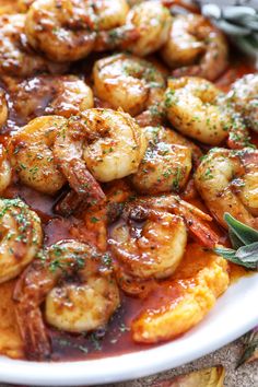 a white plate topped with shrimp covered in sauce and garnished with fresh herbs