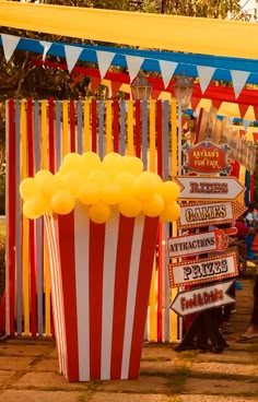 a large popcorn box with balloons in it sitting on the ground next to some signs