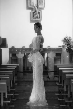 a woman in a wedding dress standing in front of pews