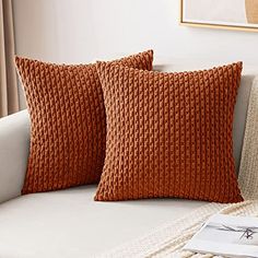 two orange pillows sitting on top of a white couch