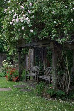 a wooden gazebo sitting next to a lush green forest filled with flowers and trees