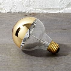 a light bulb on a wooden table with a white brick wall in the background