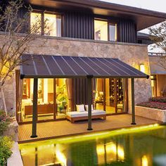 a house with a pool in front of it and lights shining on the water below