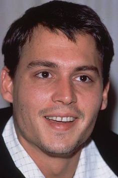 a close up of a person wearing a suit and tie with a smile on his face