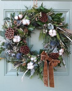 a wreath with pine cones, cotton balls and greenery