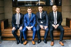 four men in suits are sitting on a bench