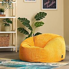 a yellow bean bag chair sitting on top of a wooden floor next to a plant