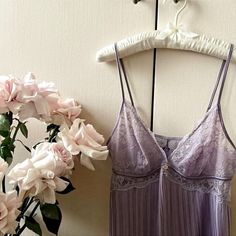 a purple dress hanging on a hanger next to pink flowers and a white flower