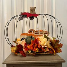 a birdcage filled with flowers and leaves on top of a table