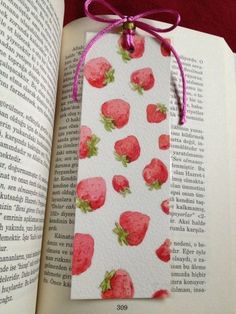 a bookmark with strawberries on it is hanging from an open book's cover