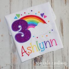 a birthday shirt with the number three on it and a rainbow in the background that says, ashlyn