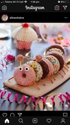 there are donuts with sprinkles and eyes on the wooden board next to pink streamers