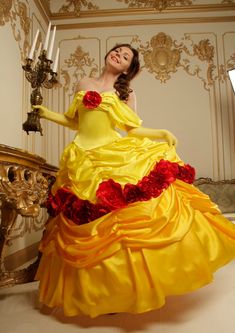 a woman in a yellow and red dress is posing for the camera with a candle