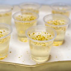 small cups filled with liquid and gold sprinkles on a white tablecloth