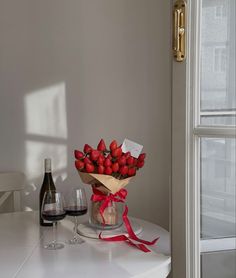 a bouquet of strawberries on a table next to a bottle of wine