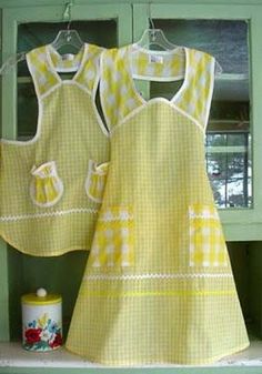 two yellow aprons hanging on a green cabinet