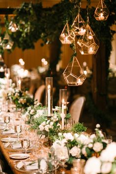 a long table with candles, flowers and greenery is set for an elegant dinner