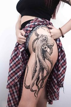 a woman with an octopus tattoo on her thigh is standing in front of a white wall