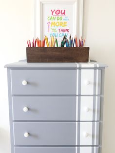 a dresser with some colorful pencils in it and a picture frame on the top