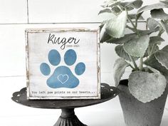 there is a sign with a paw print on it next to a potted plant