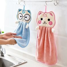 two towels hanging on the wall next to a sink with a cat and dog towel holder