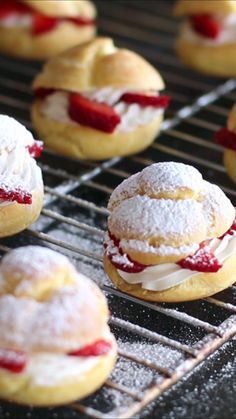 pastries with powdered sugar and strawberries are cooling on a rack