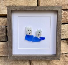 two polar bears in blue sweaters are mounted on a stone wall next to a wooden frame