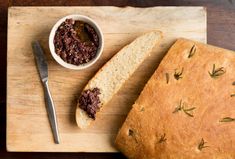 a loaf of bread sitting on top of a cutting board next to a bowl of food