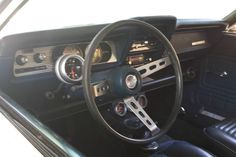 the interior of an old car with black leather seats and dash board, including steering wheel