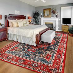 a bedroom with a bed, dressers and rug on the floor in front of a fireplace