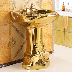 a gold pedestal sink in the middle of a bathroom