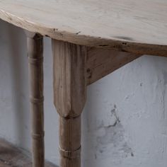 an old wooden table sitting against a white wall