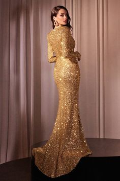 a woman in a gold gown standing on a black platform with her hands on her hips