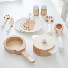 wooden kitchen utensils are arranged on a white table