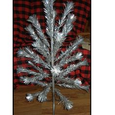 a silver christmas tree with snowflakes on it in front of a red and black checkered blanket