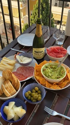 a table with plates and bowls of food on it next to a bottle of wine