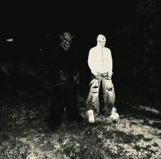 two people standing next to each other in the dark with one person wearing a mask