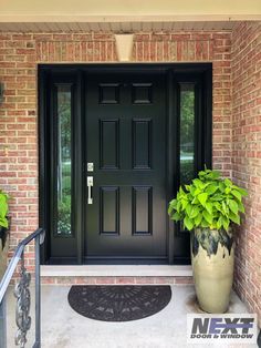 a black front door with two potted plants next to it and a welcome mat